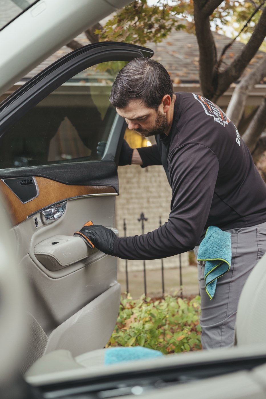 Cleaning a leather door panel with an applicator pad during an interior car detail in Tulsa
