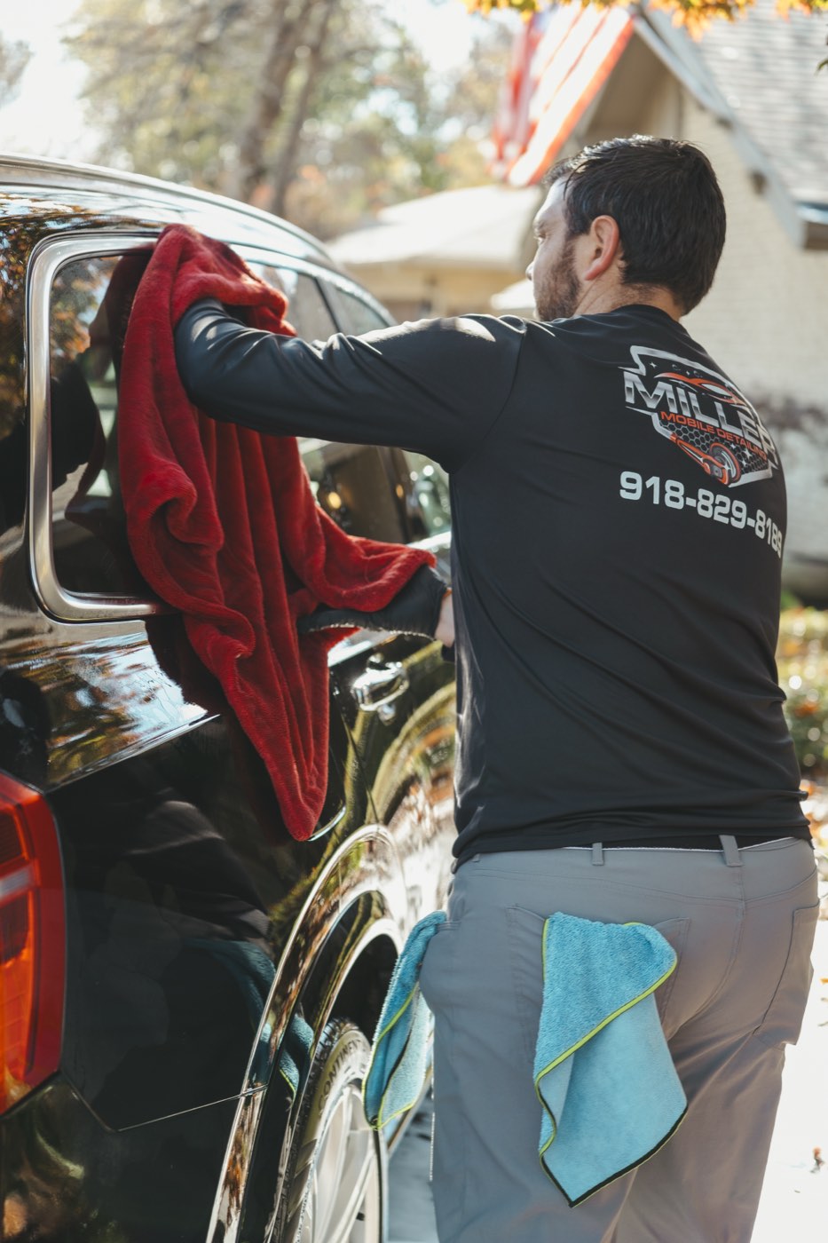 Hand drying a black SUV with a plush microfiber drying towel after a hand wash