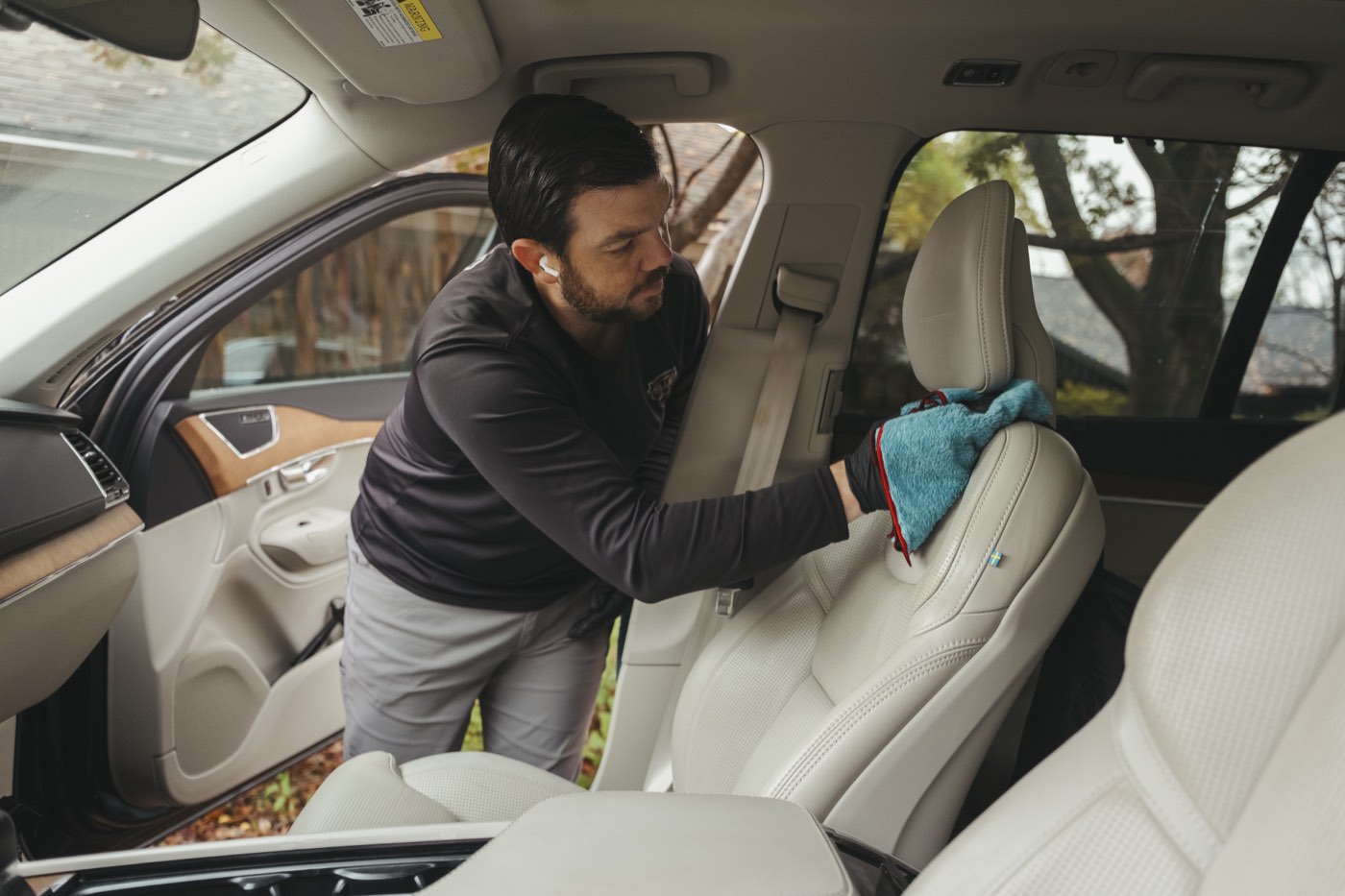 Wiping down a cream leather seat inside an SUV during a Miller Mobile Detailing interior detail